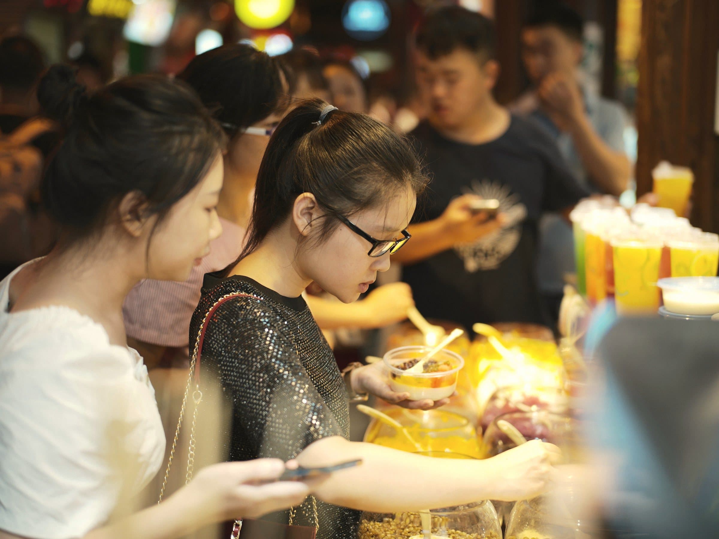 Students choosing food at a busy night-market stall.